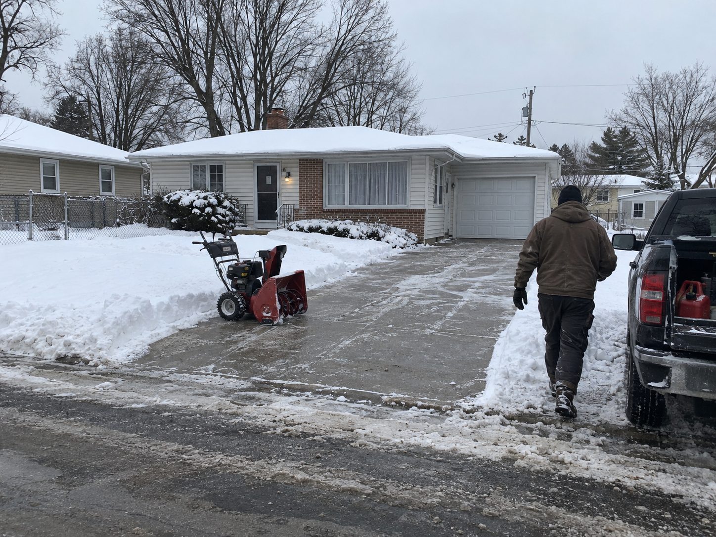 Snow removal crew finishing a cleared residential driveway in Madison, Wisconsin